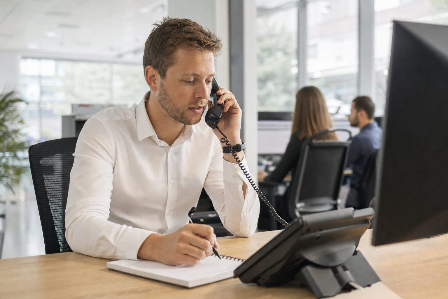 Recruiter im Büro am Telefon, daneben Notizblock und Tischapparat