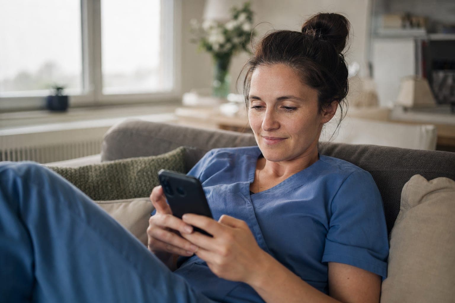 Fachkraft zuhause auf dem Sofa mit dem Telefon in der Hand